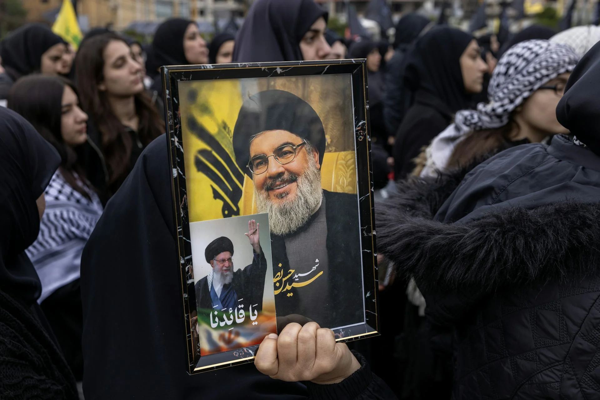 A photo of a man with a beard is held by a woman.