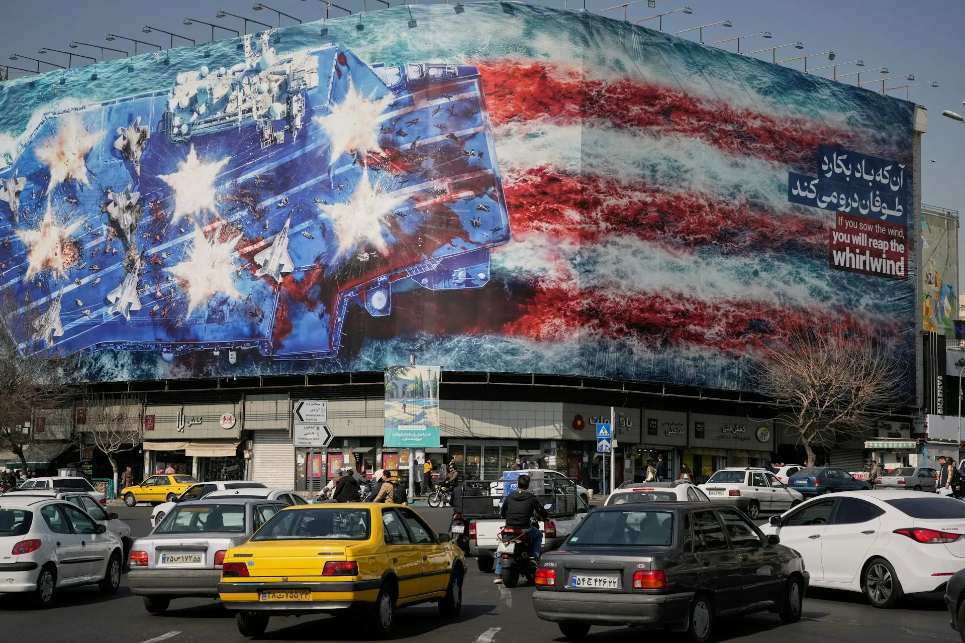 Cars drive by a building with a picture of a U.S. flag and air carrier on it.
