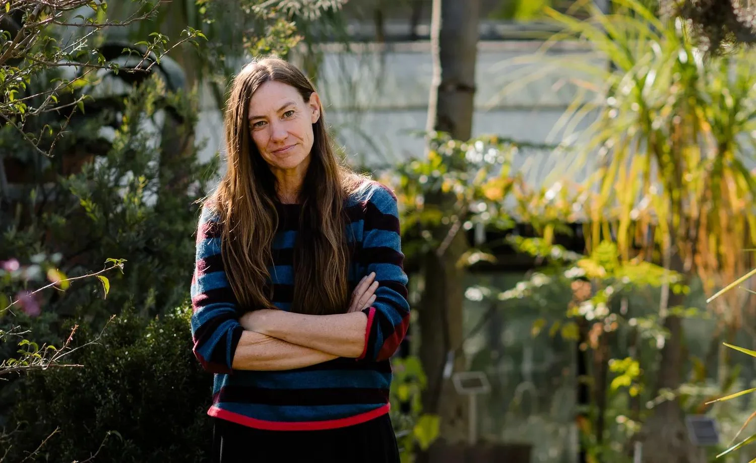 A woman with brown hair smiles with her arms crossed