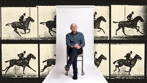 A man sits on a chair against a white backdrop, with a background featuring repeated vintage images of a person riding a horse.