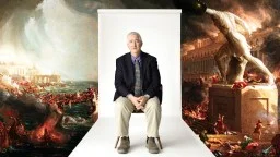 An older man in a suit sits on a chair in front of a backdrop showing a dramatic classical painting of chaos and destruction.