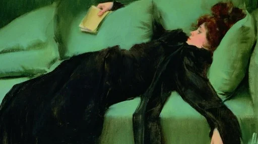 A woman in a black dress lies on a green sofa, holding a closed book in one hand, resting with her eyes closed.